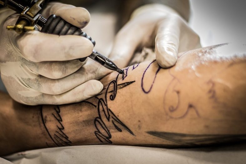 Imagen de un artista del tatuaje trabajando diligentemente en un diseño de tatuaje.